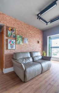 a leather couch in a room with a brick wall at PALMAS EXPERIENCE - APARTAMENTO CONTEMPORÂNEO, vista serra, na quadra do shopping in Palmas