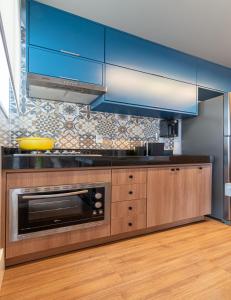 a kitchen with blue cabinets and a microwave at PALMAS EXPERIENCE - APARTAMENTO CONTEMPORÂNEO, vista serra, na quadra do shopping in Palmas