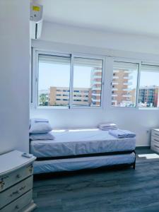 ein Schlafzimmer mit einem Bett und zwei Fenstern in der Unterkunft Apartamento Las Mercedes - Playa in Torremolinos