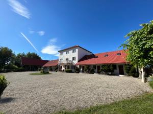 a white building with a red roof on a gravel driveway at Babie Lato in Mrągowo