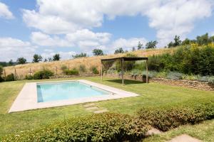 a swimming pool in a garden with a gazebo at Luminoso Fienile vista vigne in Castiglioni