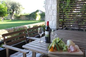 un tavolo in legno con una bottiglia di vino e un piatto di frutta di Casal Sikelio a Cassibile