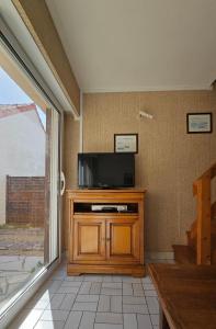 a living room with a television on a wooden entertainment center at MAISON T2 WIFI Parking Privé Les Sables d'Olonne 9mn à Pied Plage Présidents in La Rudelière