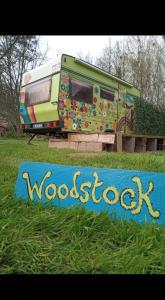 a rv is parked next to a sign in the grass at la woodstock in Xertigny +1 photo