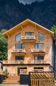 un edificio in legno con un balcone e le montagne sullo sfondo di 1740 Boutique Hotel Kazbegi a Kazbegi