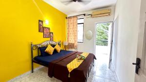 una camera con pareti gialle e un letto in una stanza di Muffys Pool Apartment a Goa