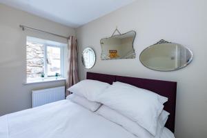 a bedroom with a bed with white sheets and a mirror at The Snug - A Quaint Mews Cottage City Centre in Wells