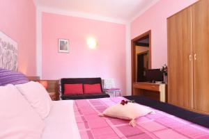 1 dormitorio con paredes rosas, 1 cama y 1 silla en Affittacamere La Rosa, en Lucca