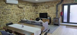 a living room with a table and a stone wall at Vilar Rural Houses - Casa dos Avós in Tangil