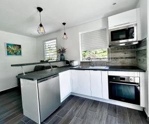 a kitchen with white cabinets and a black counter top at Le cosy Valley in Petit-Bourg