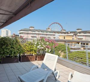 two white chairs sitting on a balcony with a ferris wheel at Hotel Morena in Lido di Jesolo