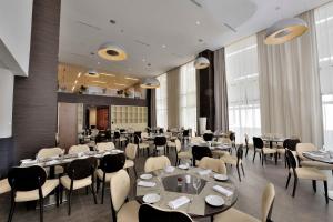 a dining room with tables and chairs and windows at Kenzi Sidi Maarouf in Casablanca