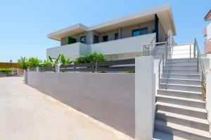 a house with a concrete wall and stairs at Masarou Suites in Afantou