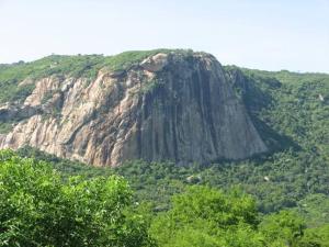a large rocky mountain with trees in front of it at Hostel da Val in Martins