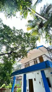 a white building with blue columns and a palm tree at Muffys Holiday Villa in Old Goa