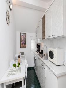 een witte keuken met een tafel en een magnetron bij Apartments Roda in Supetar