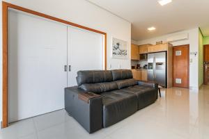 uma sala de estar com um sofá de couro e uma cozinha em Apartamento Vista Mar no Novo Campeche em Florianópolis mais 23 fotografias