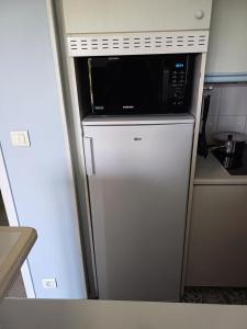 eine Mikrowelle auf einem Kühlschrank in der Küche in der Unterkunft Les Maisons de Belle Dune - maeva Home - Maison 3 Pièces 6 Personnes Confort MAE-2273 in Fort-Mahon-Plage + 9 Fotos