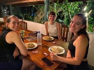 three people sitting at a table with plates of food at Green House Resort in Sigiriya