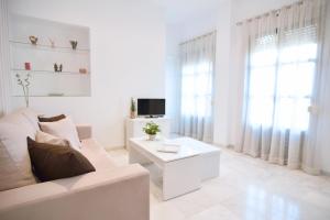 sala de estar blanca con sofá blanco y TV en Macarena Home, en Sevilla