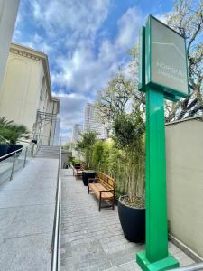 a green sign on the side of a building with benches at Hospedaria Santo André in São Paulo