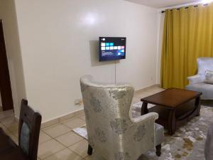 a living room with a chair and a tv at 3 Bedroom Retreat Apartment In Greatwall Gardens in Athi River