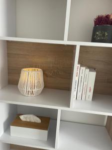 a white book shelf with a vase and books at Oasis Spa près de Disney in Nanteuil-lès-Meaux
