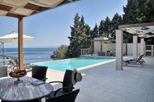 un patio con tavolo e sedie e una piscina di Corfu Dream Holidays Villa a Perama