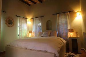 a bedroom with a large white bed with two windows at Kasbah des cyprès in Skoura +99 photos
