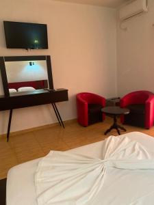 a bedroom with a bed and two chairs and a mirror at Hotel Velipoja Park in Velipojë