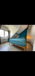 a bedroom with a blue bed in a attic at Glycine in Orléans
