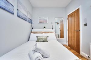 a bedroom with a white bed with a wooden door at Princess Green 2 - Portrush by the Sea in Portrush
