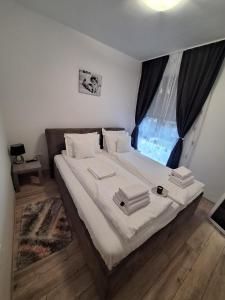 a bedroom with a bed with white sheets and a window at AquaTherm Felix in Sînmartin