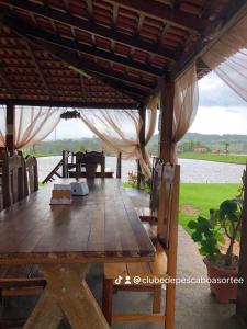 un tavolo e sedie in legno sotto un padiglione di Clube de pesca e pousada boa sorte a Itauçu