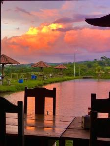 un tramonto su uno stagno con sedie e ombrelloni di Clube de pesca e pousada boa sorte a Itauçu