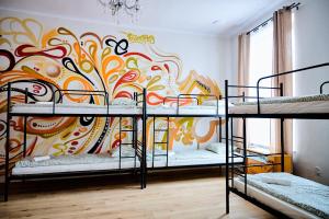 a room with four bunk beds with a colorful wall at Hostel Graffiti in Kraków