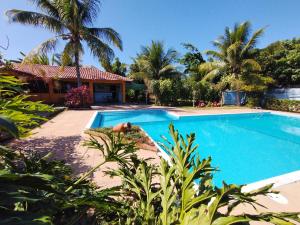 a swimming pool in front of a house with palm trees at Pousada Verdes Mares in Alcobaça