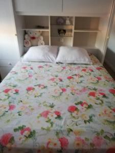 ein Bett mit einer geblümten Tagesdecke mit einem Teddybär darauf in der Unterkunft Maison neuve au cœur du Golf du Morbihan in Plougoumelen