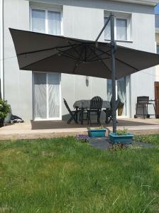 einen großen schwarzen Regenschirm auf einer Terrasse in der Unterkunft Maison neuve au cœur du Golf du Morbihan in Plougoumelen + 1 Foto