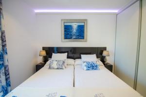 une chambre avec un lit aux draps blancs et aux oreillers bleus dans l'établissement OASIS - PALM Old Town, à Benidorm