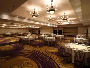 a banquet hall with white tables and chairs and chandeliers at Hotel Araiza Hermosillo in Hermosillo