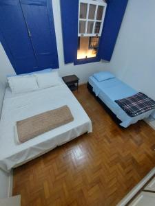 a bedroom with two beds with blue walls and a window at Casa Carmo in Ouro Preto