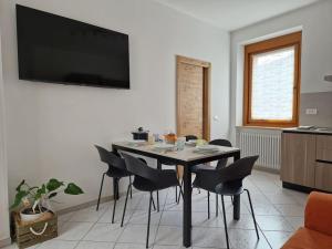 a dining room table with chairs and a television on a wall at Tiramisù Andalo in Andalo
