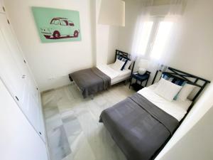 2 Betten in einem kleinen Zimmer mit Zustellbett in der Unterkunft Beachside apartment Mi Capricho Portal 7 in Sitio de Calahonda