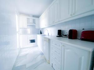 eine weiße Küche mit weißen Schränken und einem roten Gerät in der Unterkunft Beachside apartment Mi Capricho Portal 7 in Sitio de Calahonda + 42 Fotos