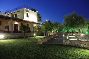 a house with a stone wall and a yard at night at Casal Sikelio in Cassibile