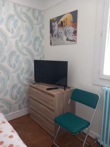 a bedroom with a tv on a dresser and a chair at Les Cyclamens in Cosne-Cours-sur-Loire