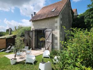 ein altes Steinhaus mit Terrasse und Stühlen in der Unterkunft La Grange du Moulin in Noyers-sur-Cher