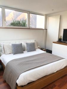 Un dormitorio con una gran cama blanca con dos ventanas. en Attico con vista panoramica sul lago - due camere, en Lugano
