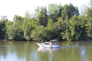 a boat on a river with trees in the background at Calme au bord de l'eau in Laroche-Saint-Cydroine